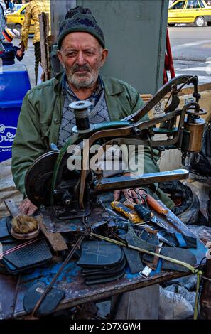Man repairing shoes outside Ardabil bazaar in a street stall, Ardabil bazaar, Ardabil, Iran Stock Photo