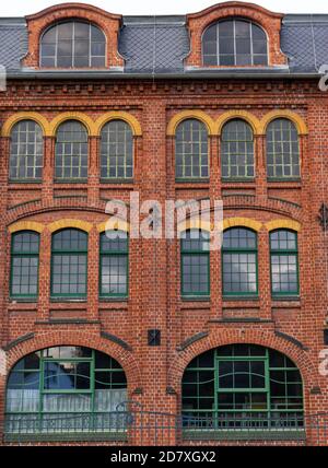 red brick facade of old industrial building with large glass windows Stock Photo