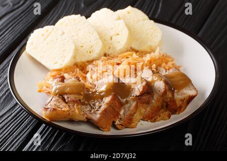 Roasted pork with stewed sauerkraut and dumplings close-up in a plate on the table. horizontal Stock Photo