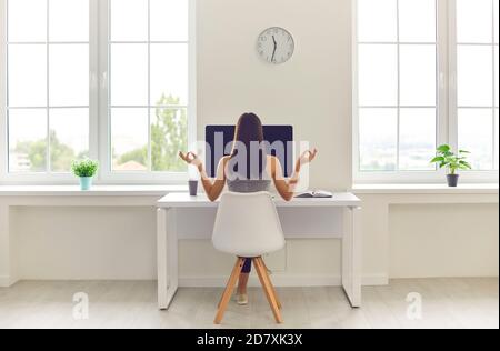 Woman taking break from work and meditating sitting at office table with computer and coffee Stock Photo