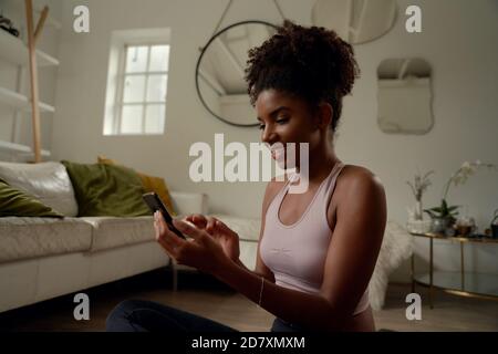 Happy young woman doing yoga and using cell phone sitting on the floor Stock Photo