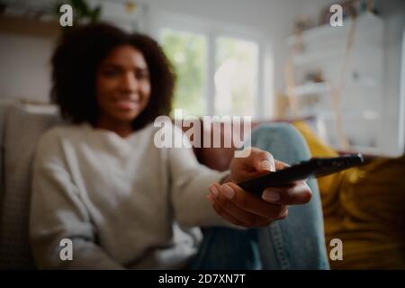 Closeup of woman hand holding remote control while sitting at home watching television alone Stock Photo