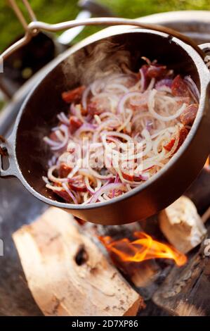 Spicy chorizo and onion stew cooking over fire pit Stock Photo