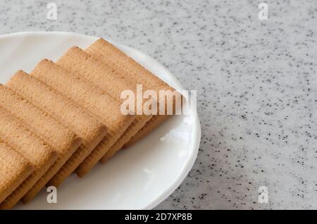 Rectangular shortbread cookies and chocolates in a white plate on a marble top. Stock Photo