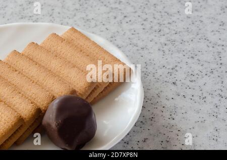 Rectangular shortbread cookies and chocolates on a white saucer. Stock Photo