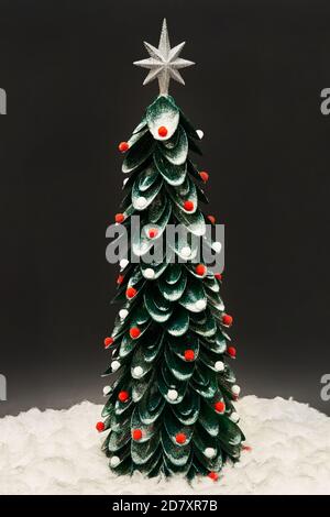 Handmade Christmas tree from plastic spoons decorated with multi-colored soft Christmas toys and sparkles on the dark background. New Year Tree. Stock Photo