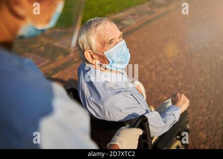 Cropped photo of a person rolling elderly in wheelchair Stock Photo