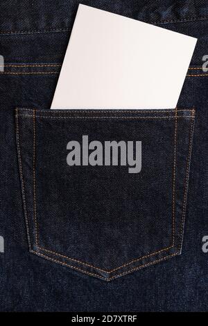 Blank white card in the back pocket of dark blue jeans. Closeup. Copy space
