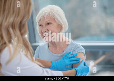 Long-haired female nurse making vaccination to an elderly woman Stock Photo