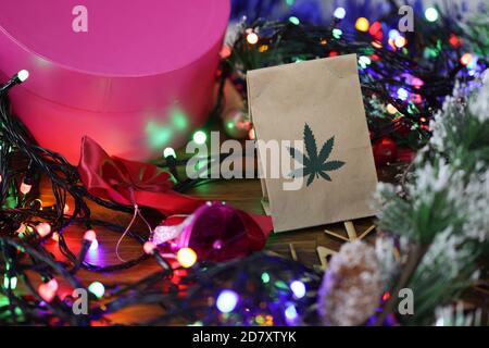 Paper bag with marijuana lies on table among new year's tinsel, gifts, garlands Stock Photo