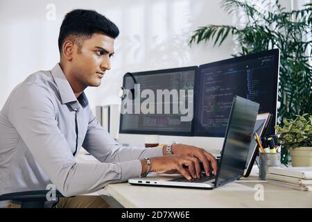 Programmer typing on laptop Stock Photo