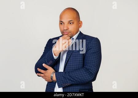 Portrait of an unhappy young African American guy businessman, thinking looking tired and bored with depression problems with crossed arms. Standing on a gray background Stock Photo