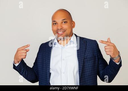 Portrait of young african american guy businessman smiling confidently showing and pointing with fingers teeth and mouth. Health concept. Standing on a gray background Stock Photo
