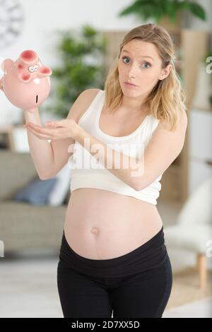 young unhappy woman emptying her piggybank savings Stock Photo