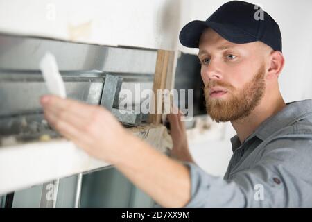 construction worker repairing window in house Stock Photo