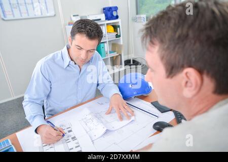 Two men at desk looking at blueprints Stock Photo