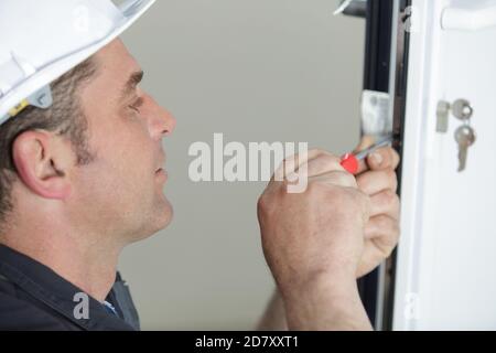 worker fasten a handle to a plastic window Stock Photo