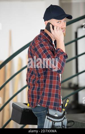 busy handyman arriving at property talking on his smartphone Stock Photo