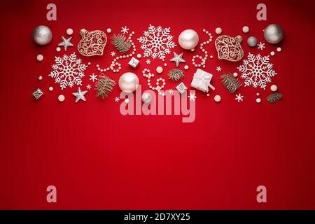 Christmas border. New Year decorations on red copy space background. White ornaments, flat lay. Stock Photo