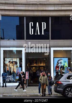 People wearing face masks walk past the Gap store on Oxford Street, London Stock Photo