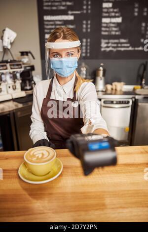 Charming barista in stylish uniform taking pos terminal for payment Stock Photo