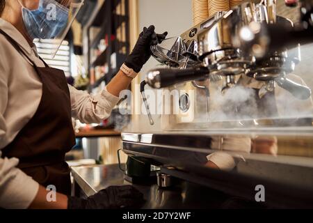 Woman waiter cleaning coffee machine in the cafe bar Stock Photo