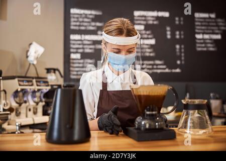 Professional barista preparing coffee using chemex pour over coffee maker  and drip kettle. Young woman making coffee. Alternative ways of brewing  coffee. Coffee shop concept. Stock Photo