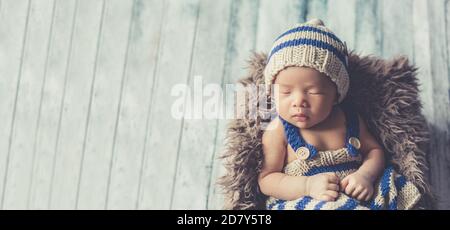 Adorable newborn baby sleeping in cozy room. Cute happy infant baby portrait with sleepy face in bed. Soft focus at the baby eyes. Newborn nursery Stock Photo