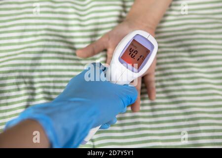 Doctor measures temperature of child on hand. Digital thermometer showing high indicator of over 40 degrees Celsius. Body's defensive reaction, immuni Stock Photo