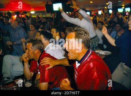British football fans World Cup 1998. Supporters watching a penalty shoot out between England and Argentina that decided the game, Argentina won 4–3 after two English kicks were saved. England was  knocked out of the World Cup. Watching on a multi screens in a television room of the Sports Bar, London 1990s UK HOMER SYKES Stock Photo