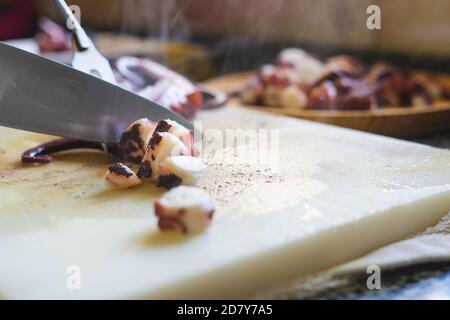 Cutting octopus with knife on kitchen table. Concept of Seafood. Stock Photo