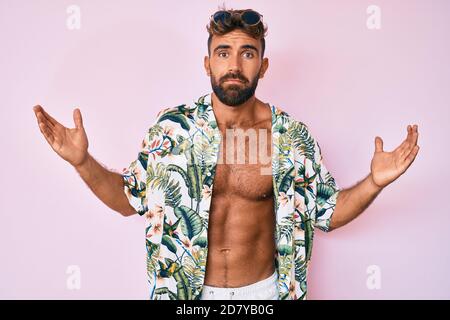 Young hispanic man wearing casual summer clothes serious face thinking about question with hand on chin, thoughtful about confusing idea Stock Photo