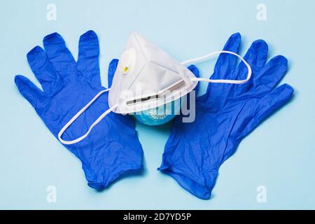 Medical mask with valve, gloves and a toy globe on the table. The concept of wearing personal protective equipment around the world Stock Photo