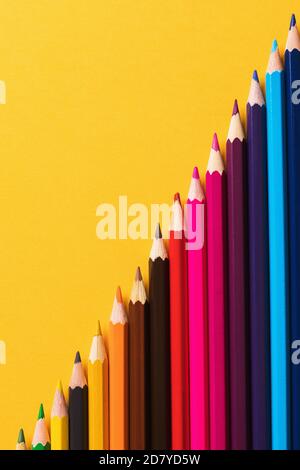 Colored pencils on yellow background, top view Stock Photo