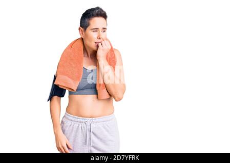 Young woman with short hair wearing sportswear and towel using smartphone looking stressed and nervous with hands on mouth biting nails. anxiety probl Stock Photo