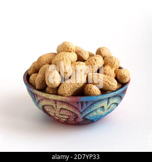 clay bowl with peanuts in shell on white background Stock Photo