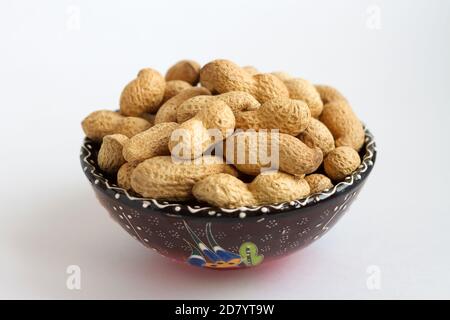raw peanuts in shell on clay cup on white background Stock Photo