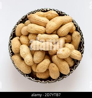 Raw peanuts in shell on clay cup. Top view Stock Photo