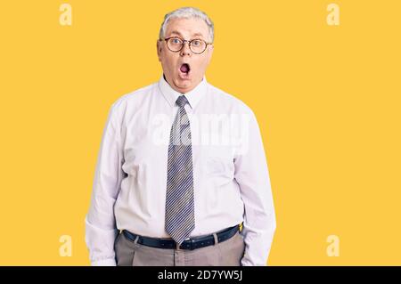 Senior grey-haired man wearing business clothes afraid and shocked with surprise expression, fear and excited face. Stock Photo