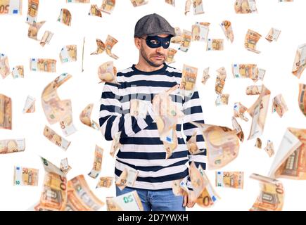 Young handsome man wearing burglar mask pointing aside worried and nervous with forefinger, concerned and surprised expression Stock Photo