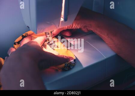 Woman hands using the sewing machine to sew the face mask during the coronavirus pandemia. Stock Photo