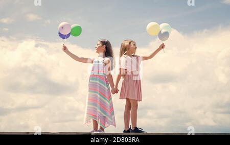 summer vacation. small girls embrace. love and support. concept of sisterhood and friendship. family bonding time. best friends with balloon. two sisters hold party balloon. happy childhood. Stock Photo