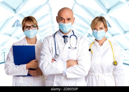 Shot of female and male doctors standing together on the clinic’s foyer while looking at camera. Medical team. Doctors wearing face masks for preventi Stock Photo