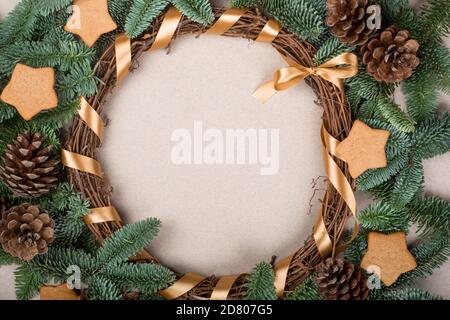 Christmas decorative wreath with noble fir tree twigs pine cones and gingerbread cookies on craft paper background with copy space for text Stock Photo