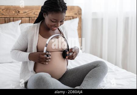 Smiling relaxed pregnant woman, future mom with tummy puts headphones on  belly for baby to listen to music. Pregnancy 24696873 Stock Photo at  Vecteezy