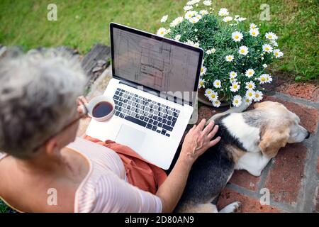 Top view of senior woman architect with laptop working outdoors in garden, home office concept. Stock Photo