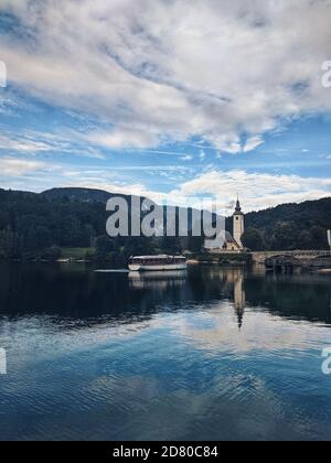 Scenic view of beautiful mountains landscape and church reflected on Bohinj Lake Stock Photo