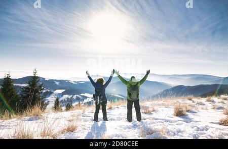 Rear view of senior couple hikers in snow-covered winter nature, stretching arms. Stock Photo