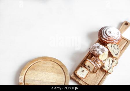 Different fresh pastries are cut on a wooden stick . On a light background, space for text. Stock Photo