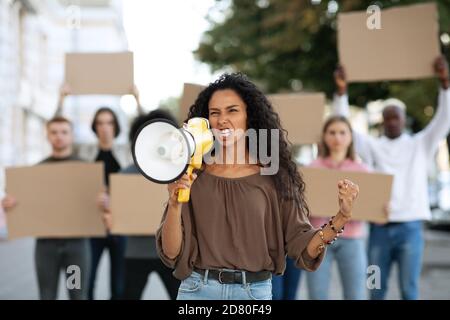 Multiracial protestors striking on the street, holding megaphone and placards Stock Photo